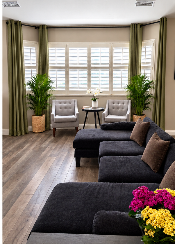 The bay window at Sunrise Care, with two armchairs, potted palms, and a white orchid